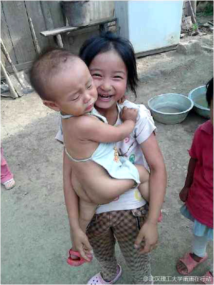 7月17日,“蛋蛋在行動(dòng)”團(tuán)隊(duì)田壩分隊(duì)對(duì)支教的孩子們進(jìn)行了家訪,并給孩子們帶去了簡(jiǎn)單的衣物。一名隊(duì)員說:“現(xiàn)在終于了解孩子們?yōu)槭裁磿?huì)遲到,還有為什么常有‘小黑手’和小傷口,這里的山路真的很難走,有的孩子上學(xué)前還得先給牛割草……”圖上的小女孩雖然年齡不大,但照顧弟弟已經(jīng)十分嫻熟。