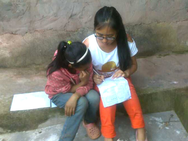 西昌涼山州喜德縣當?shù)氐暮⒆佣夹枰獛椭依锔赊r(nóng)活,只有在一天的勞作結束以后,才能來接受隊員們的功課輔導。圖為四川農(nóng)業(yè)大學“彝路陽光”團隊隊員在給一個剛剛勞作回來的孩子講解作業(yè)。